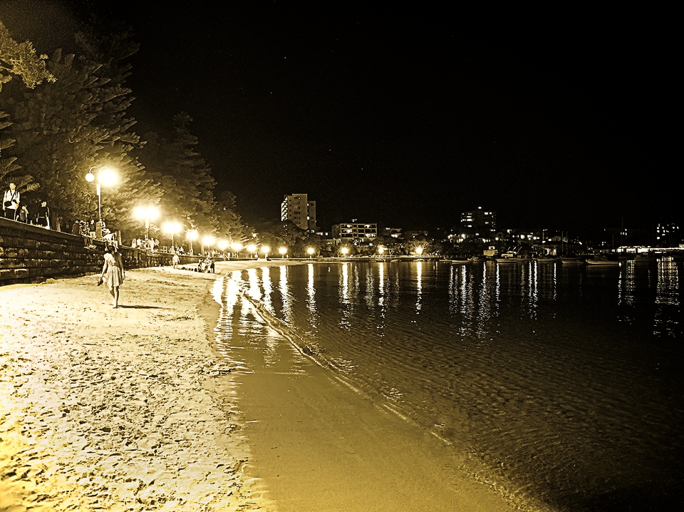 Girl walking along Manly Cove Beach, on a hot night